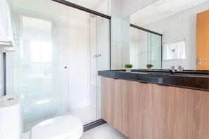 A modern bathroom with a glass shower enclosure, a wooden vanity, and a large mirror.