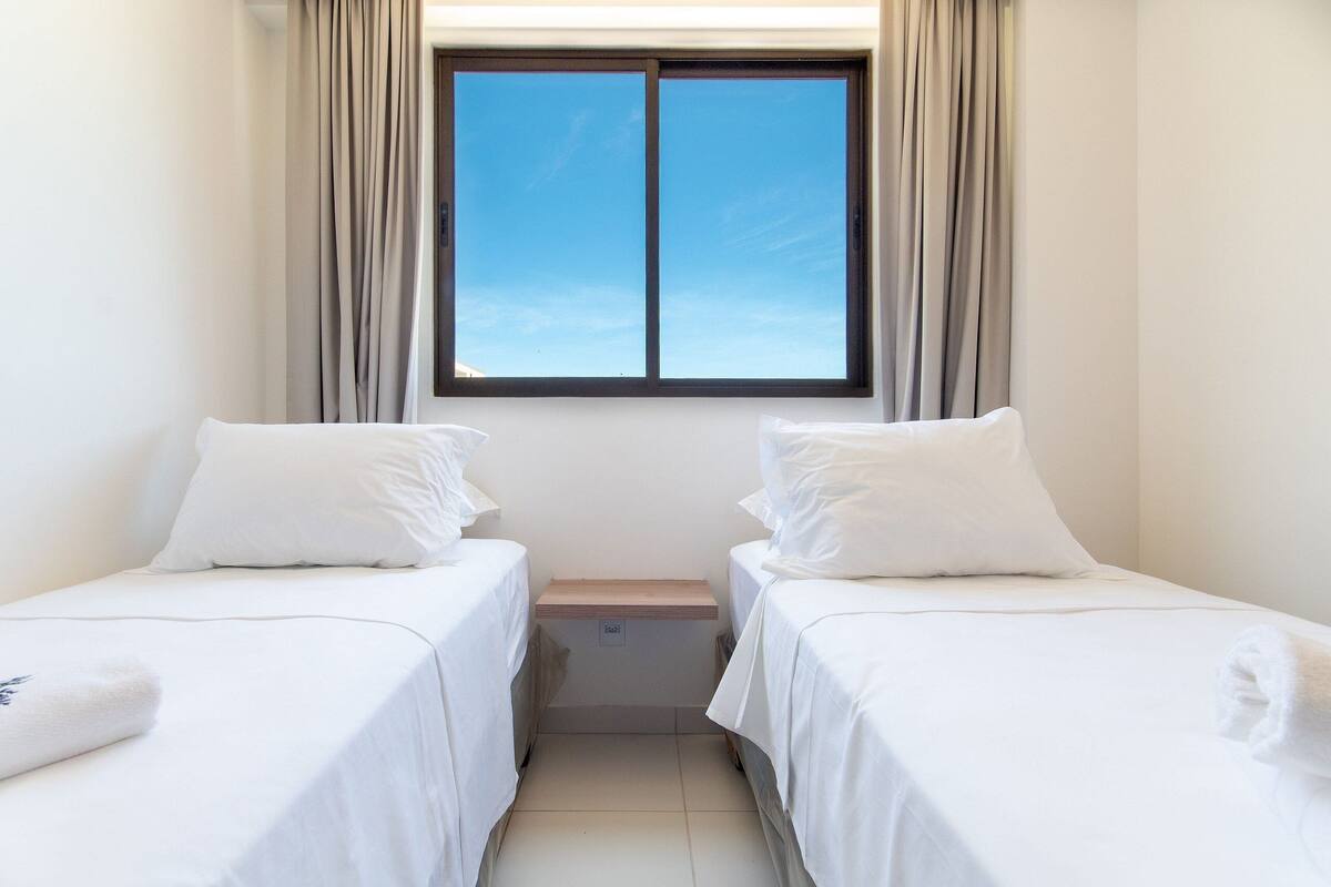 Une chambre double avec deux lits, une fenêtre avec des rideaux et une petite table de chevet.