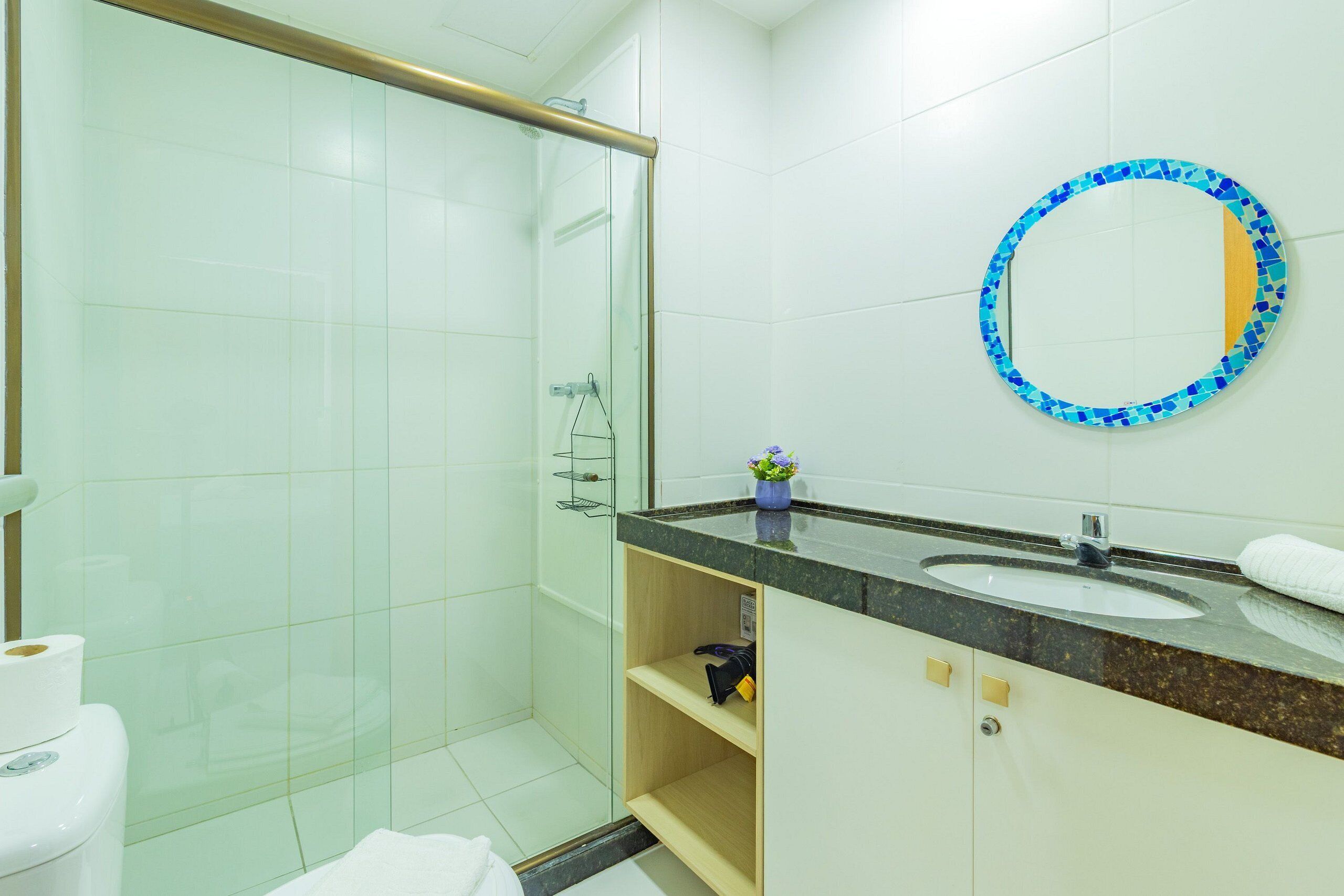 A bathroom with a glass shower enclosure, a sink with a mirror, and a toilet.