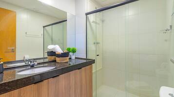 A modern bathroom with two sinks, a glass shower enclosure, and a wooden vanity.