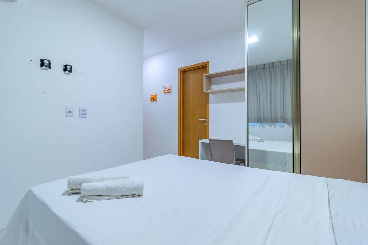 Une petite pièce propre, avec un lit, un bureau et une porte.
