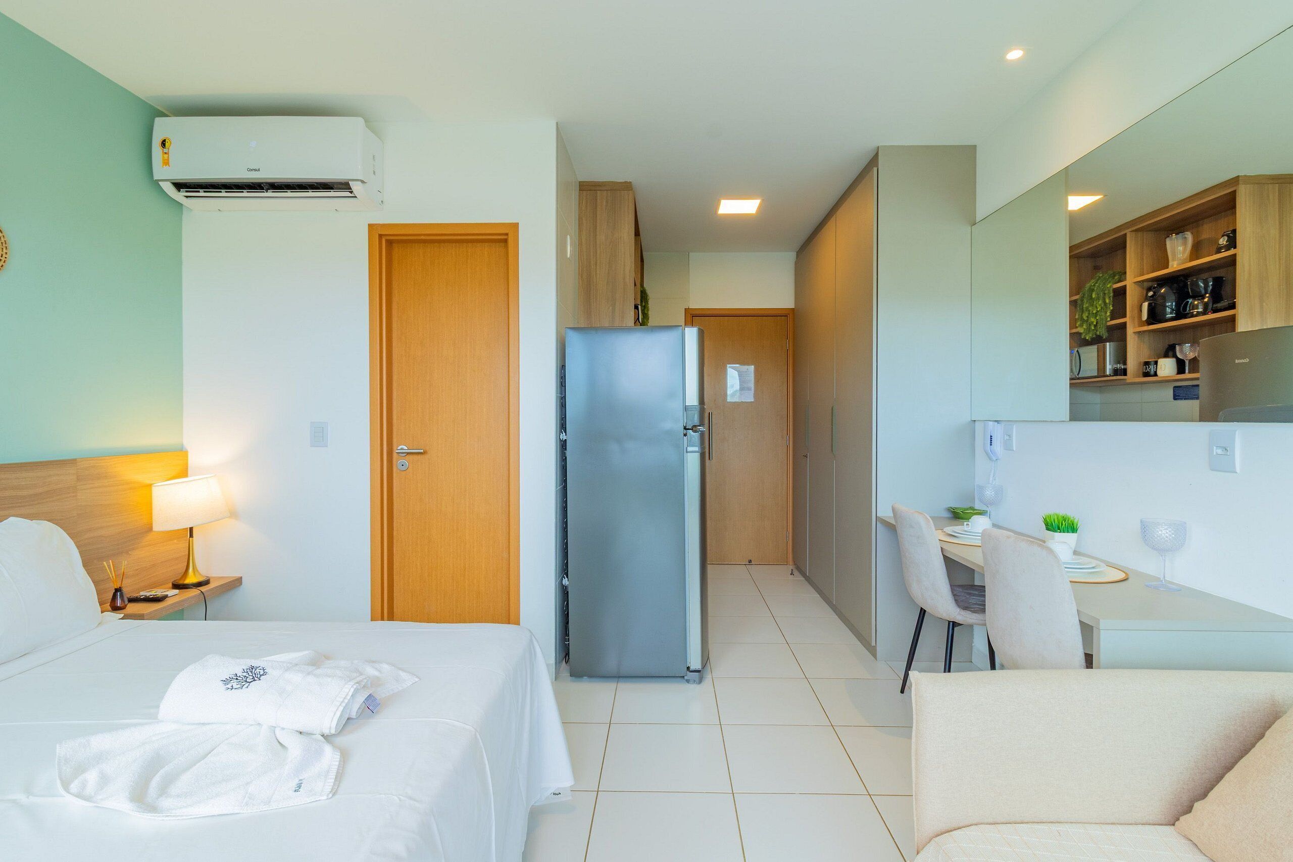 Ein Hotelzimmer mit Bett, Schreibtisch, Kühlschrank und einer Küchenzeile.