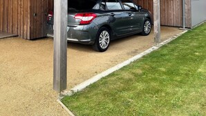 Un edificio moderno con un área de estacionamiento techada y un coche dentro.