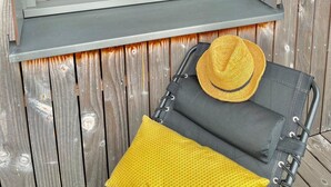 Una habitación con cabecera de madera, cama con ropa de cama color turquesa y ventana con vista a una terraza de madera.