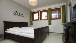 Ein Schlafzimmer mit einem hölzernen Bett, einem an der Wand montierten Fernseher und einem Fenster mit Vorhängen.