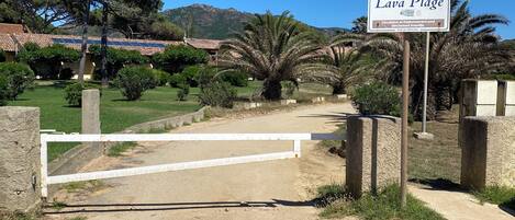 A sign for 'Lava Plage' with a gate and surrounding greenery.