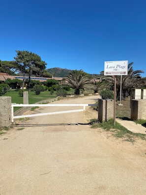 A sign for 'Lava Plage' with a gate and surrounding greenery. - Lava Plage - Feet in the water (appietto)
