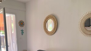 A modern living room with a sofa, a round mirror, and decorative wall art. - Lava Plage - Feet in the water (appietto)
