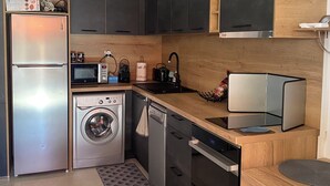A modern kitchen with a stainless steel refrigerator, microwave, washing machine, and dishwasher. - Lava Plage - Feet in the water (appietto)