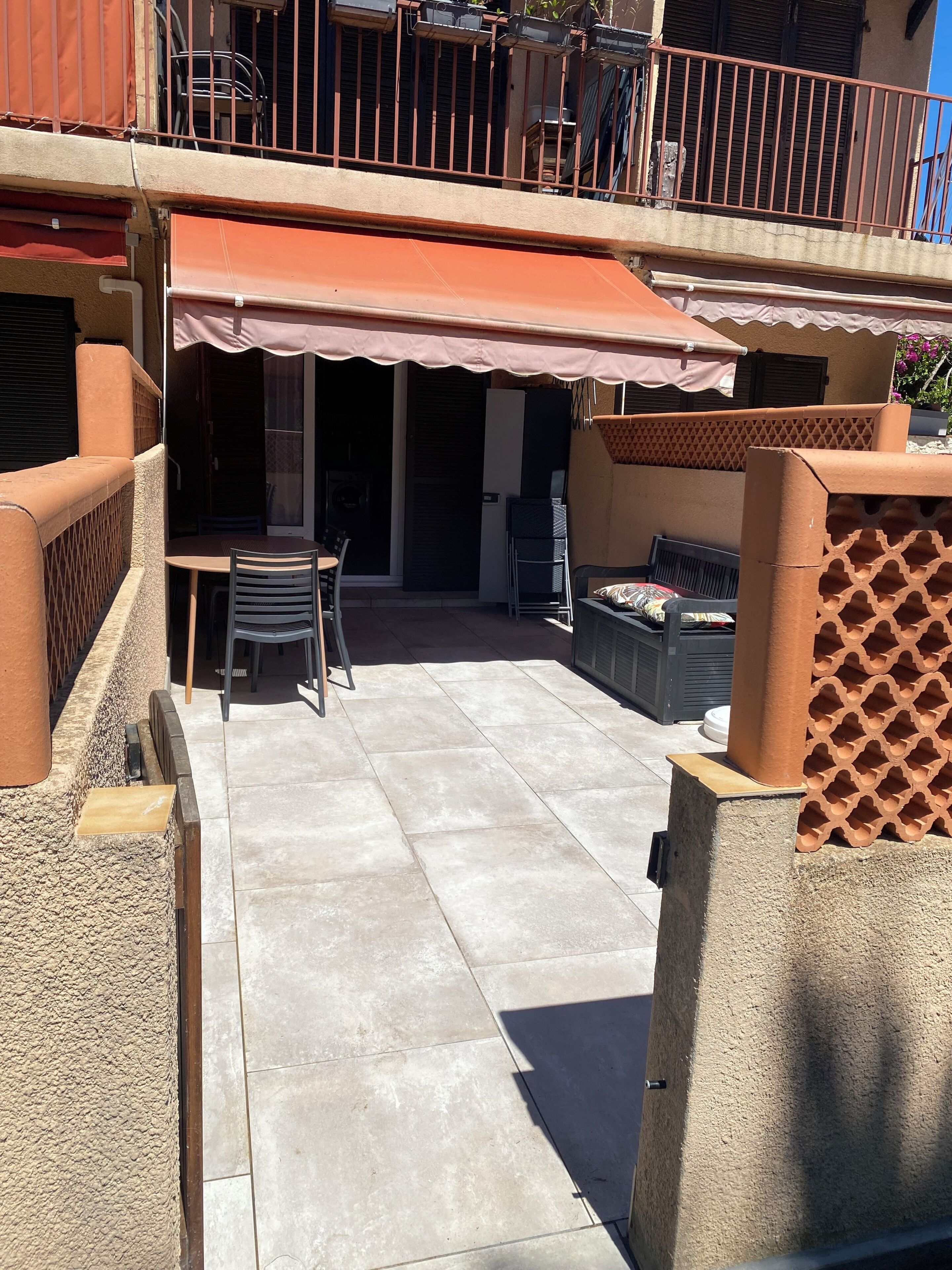 A patio area with a table and chairs, a covered seating area, and a view of the street.