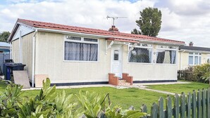 Ein eingeschossiges Haus mit rotem Ziegeldach, einem Backstein-Schornstein und einer kleinen Veranda.