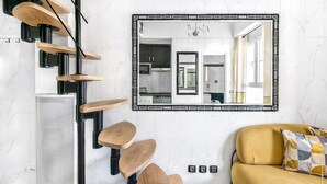 A modern kitchen with a large mirror, wooden stools, and a yellow sofa. - Studio Colisee - Champs Elysees by B'Your Home (Paris)