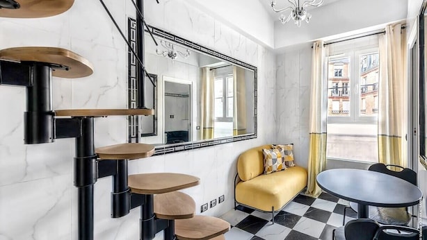 A modern interior with a checkered floor, a sofa, a dining table, and a chandelier. - Studio Colisee - Champs Elysees by B'Your Home (Paris)
