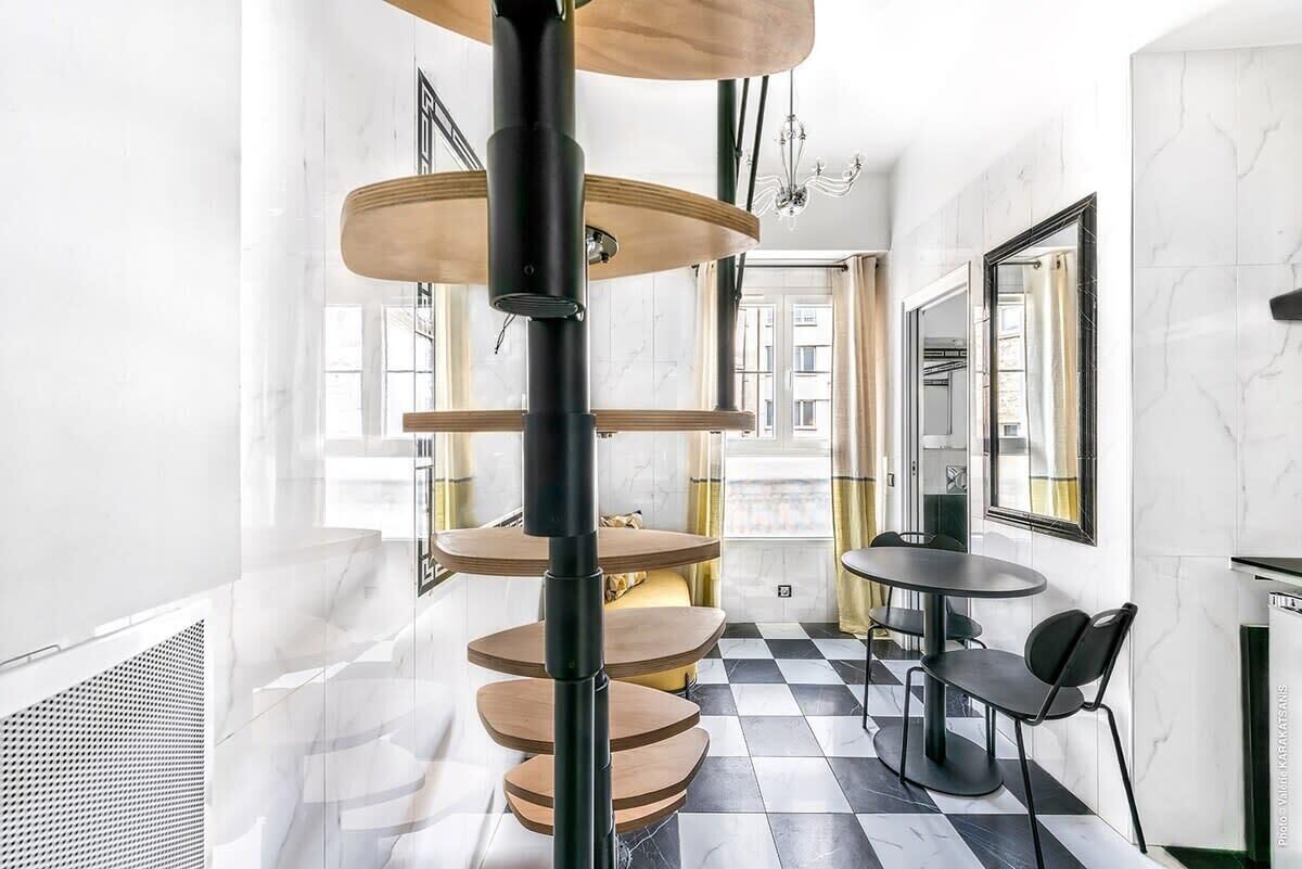 A modern interior with a spiral staircase, checkered floor, and a dining area with chairs.