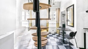 A modern interior with a spiral staircase, checkered floor, and a dining area with chairs. - Studio Colisee - Champs Elysees by B'Your Home (Paris)