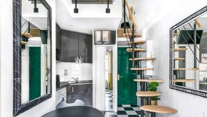 A modern kitchen with a black and white checkered floor, a black dining table, and a green door leading to another room. - Studio Colisee - Champs Elysees by B'Your Home (Paris)