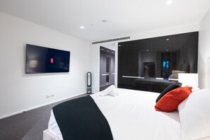 Een moderne hotelkamer met een groot bed, een flatscreen televisie aan de muur, een spiegel en een deur naar de badkamer.
