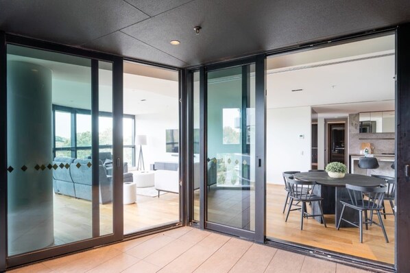 A modern interior with a dining area, a sofa, and a view through large glass doors.