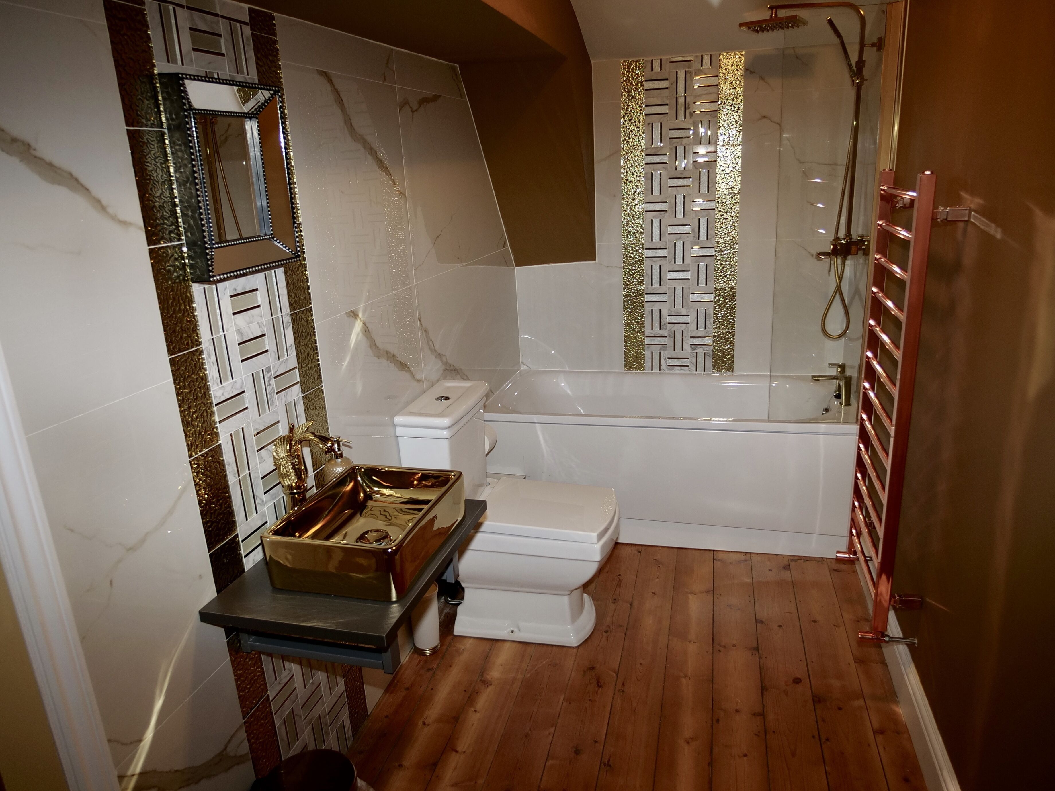 Ein Badezimmer mit Marmorwand, Toilette in Weiß, einer Badewanne und Holzboden.