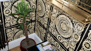 Una habitación con una planta en maceta, un libro y una estantería decorativa con copas de cristal.