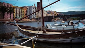 A wooden boat docked at a harbor with buildings and a bridge in the background. - Large, Authentic 2-bed Apartment, Panoramic Views (Bosa)