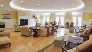 A spacious living room with a fireplace, comfortable seating, and a large window providing natural light. - Mini Weeks Stays Available Sunset Island 45 Sunset Island Drive (Ocean City)