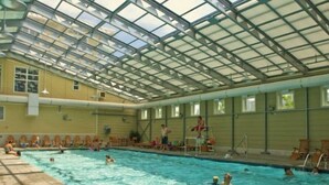 An indoor swimming pool with a glass ceiling, surrounded by lounge chairs and a tiled deck. - Mini Weeks Stays Available Sunset Island 45 Sunset Island Drive (Ocean City)