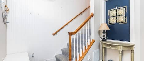 Un escalier avec des rampes en bois et un tapis à motifs à sa base.