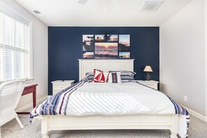 A bedroom with a bed, a nightstand, a lamp, a chair, and a window. - Mini Weeks Stays Available Sunset Island 45 Sunset (Ocean City)