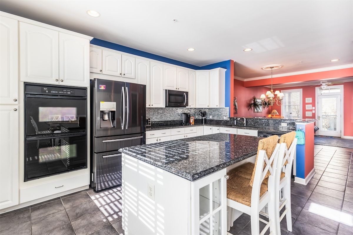 A modern kitchen with white cabinetry, a granite countertop, and stainless steel appliances.