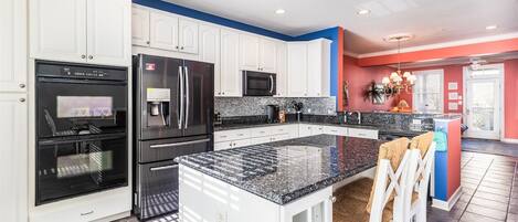 A modern kitchen with white cabinetry, a granite countertop, and stainless steel appliances.