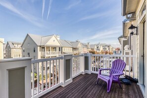 A wooden deck with a white railing, a purple chair, and a view of neighboring houses.