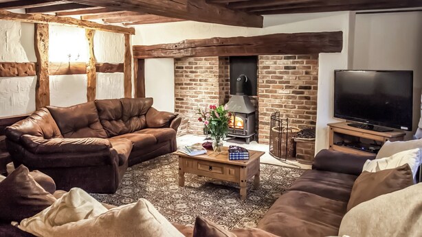 A cozy living room with leather sofas, a fireplace, and a TV. - 7 bedroom accommodation in Blackden, near Crewe (Blackden, near Crewe)