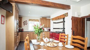 A dining area with a wooden table set for four, surrounded by wooden chairs. - 7 bedroom accommodation in Blackden, near Crewe (Blackden, near Crewe)
