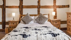 A bedroom with a wooden ceiling, a bed with a patterned blanket, two bedside lamps, and wooden nightstands. - 7 bedroom accommodation in Blackden, near Crewe (Blackden, near Crewe)