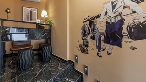 A modern hotel lobby with a marble staircase, a wall-mounted air conditioner, and a mural of stylized figures. - Clyde Athens by Nin&Bau (Athens)