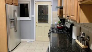 Eine kleine Küche mit Holzausstattung, einem Edelstahlkühlschrank, einem Herd und einer gefliesten Spritzschutzwand.