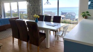 Un comedor con una mesa, sillas y vistas al mar.