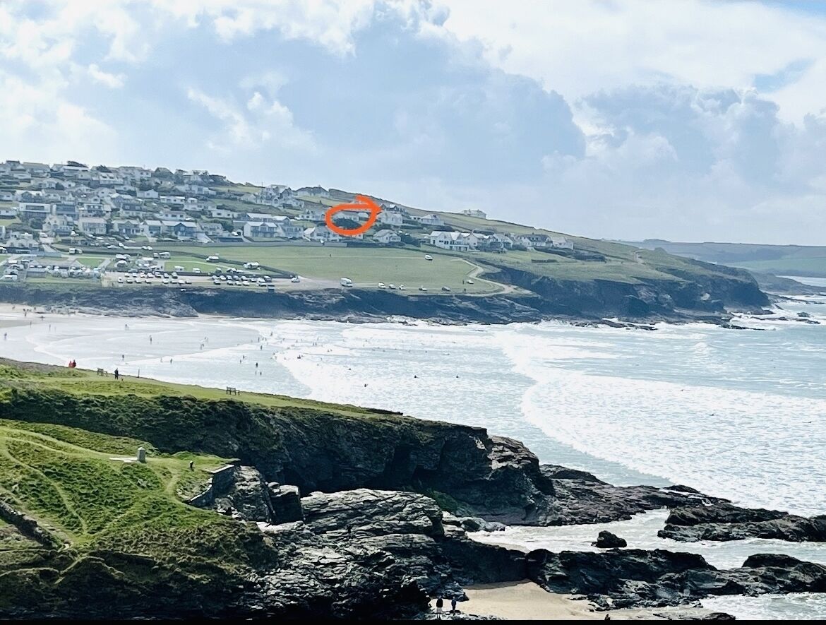 A coastal town with a beach, rocky cliffs, and houses in the background.