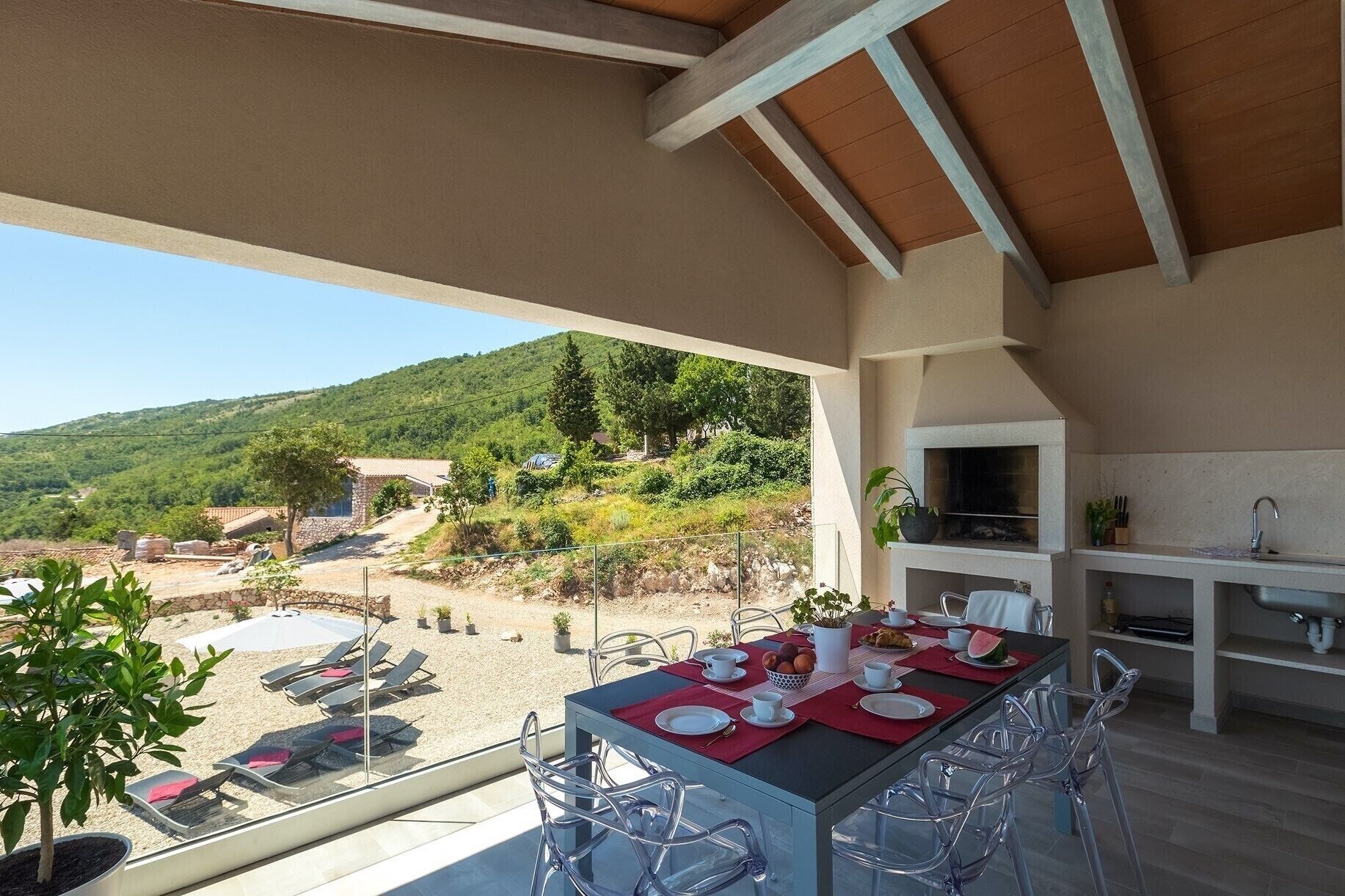 An outdoor dining area with a table set for four, overlooking a scenic hillside.