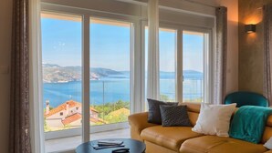 A room with a sofa and a table, large windows with a view of a body of water and buildings. - Penthouse with excellent sea views (Brsec)
