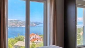 A bedroom with a large window offering a view of a coastal landscape. - Penthouse with excellent sea views (Brsec)
