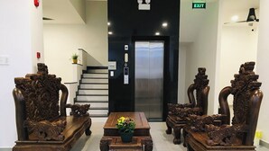 A lobby with ornate wooden furniture, a staircase, and an elevator. - Kalia Hotel (Phu Quoc)