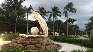 A fountain with a spherical structure on top, surrounded by rocks and greenery. - Kalia Hotel (Phu Quoc)