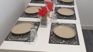 Uma mesa de jantar posta com pratos, copos e um arranjo central.