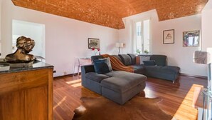 A spacious living room with a brick ceiling, a large sectional sofa, and a wooden floor.