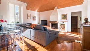 A spacious living room with a large gray sofa, a television, and a fireplace.