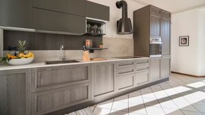 A modern kitchen with grey cabinetry, a stainless steel sink, and a built-in oven.
