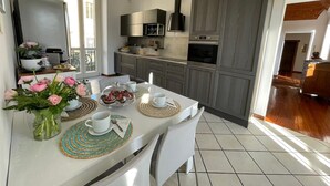 A modern kitchen with grey cabinets, a built-in oven, and a microwave. There is a dining table with placemats and a vase of flowers.