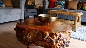A living room with a large wooden coffee table, two grey sofas, and a wicker side table. - Deluxe 4/5 Bed Hot Tub Cinema Room 15 (Halstead)